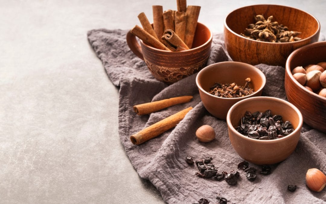 Bowls of cinnamon sticks, cloves, star anise, dried berries, and hazelnuts on a gray cloth. Chinese Herbal Medicine.